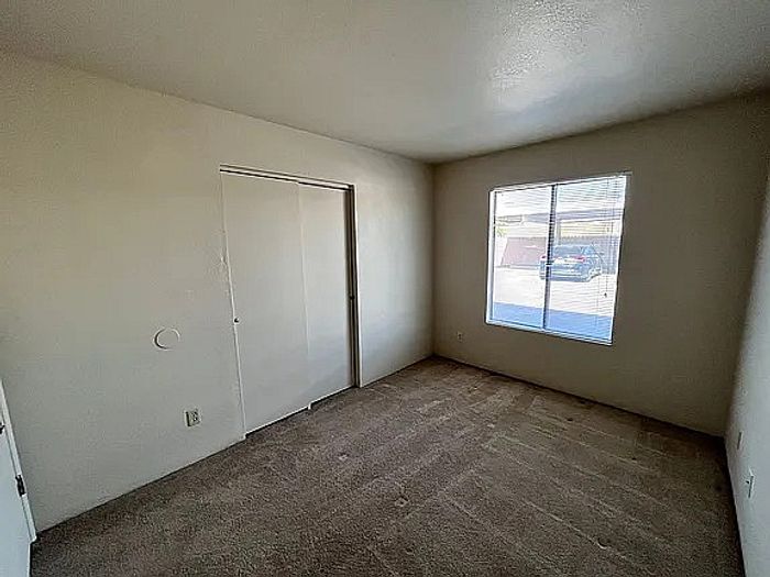 Bright and inviting bedroom with plush carpet, ample closet space, and large window allowing natural light.