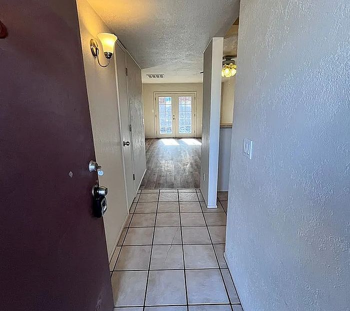 Inviting apartment entrance with tiled flooring leading to a sunlit living area with French doors.