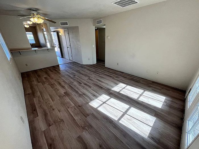 Bright and inviting living space with elegant wood flooring and ceiling fan, perfect for cozy gatherings.