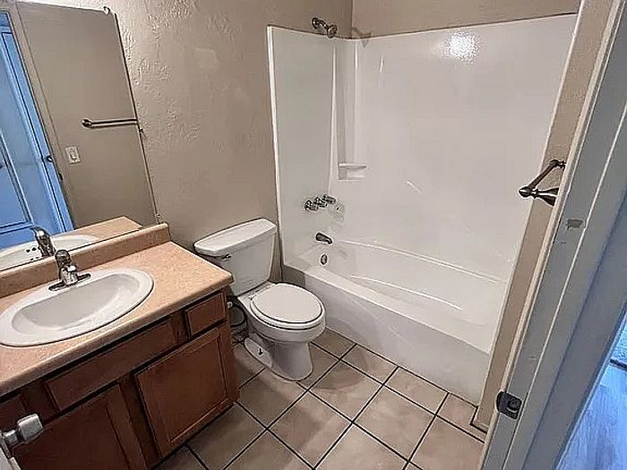 Modern bathroom with sleek tile flooring, a full bathtub, and elegant wooden cabinetry providing ample storage space.