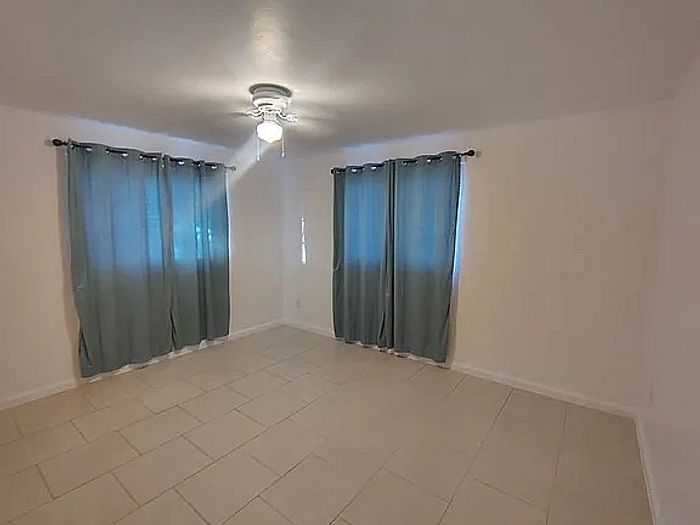 Bright and spacious room with elegant tile flooring and inviting natural light, ideal for a cozy bedroom or versatile office space.