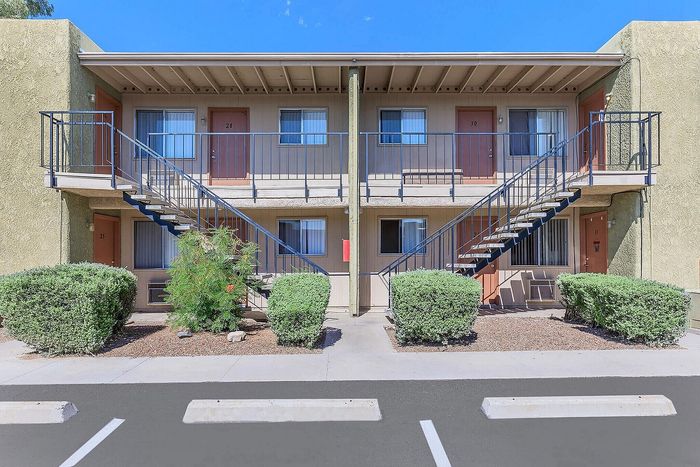 Inviting apartment building exterior with charming balconies and lush greenery, offering a warm welcome.