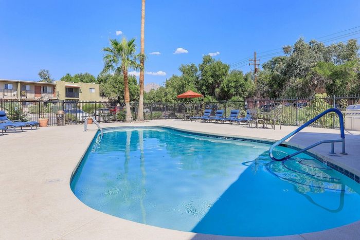 Inviting swimming pool with sleek lounge chairs and vibrant palm trees, perfect for relaxation and leisure.