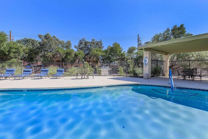 Inviting outdoor pool area with comfortable lounge chairs, shaded seating, and lush greenery offering a perfect relaxation spot.
