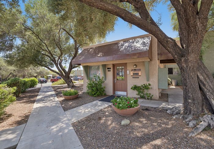 Charming apartment entrance surrounded by lush greenery and inviting pathways, perfect for a peaceful neighborhood setting.