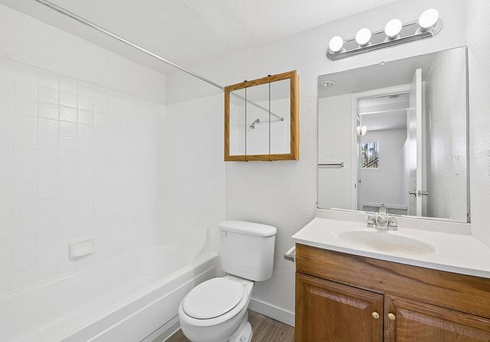 Bright and modern bathroom featuring a pristine bathtub, sleek vanity with ample storage, and a large mirror with stylish lighting.