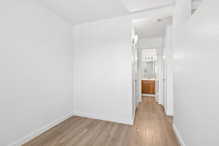 Bright hallway featuring sleek hardwood floors leading to a modern bathroom with elegant fixtures.