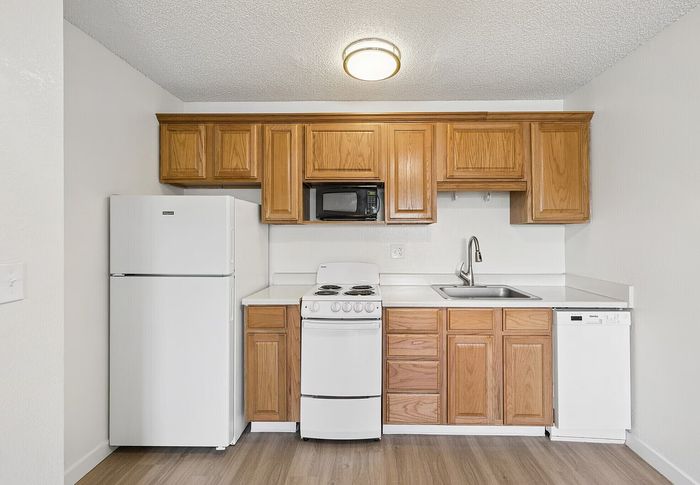 Elegant kitchen with wooden cabinetry, modern appliances, and pristine white countertops providing a warm and functional cooking space.