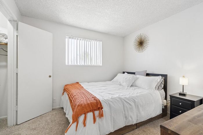 Cozy bedroom featuring plush bedding, modern decor accents, and natural light through the window, creating a serene and inviting atmosphere.