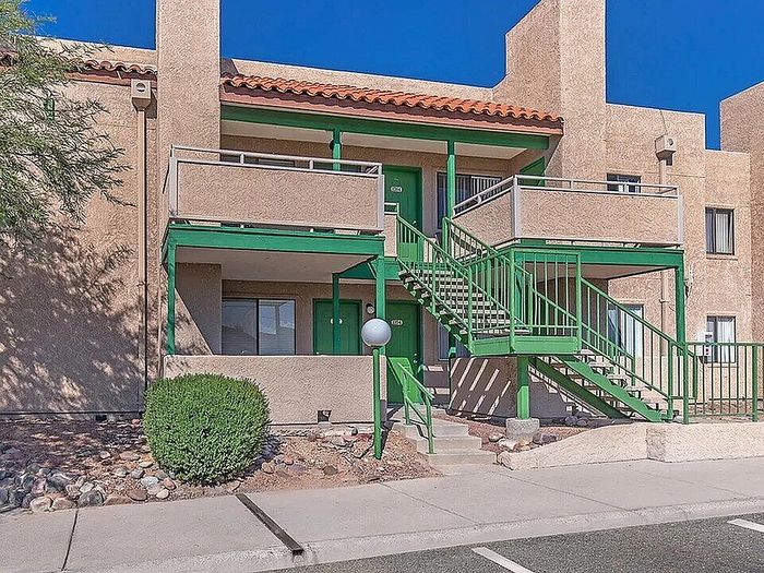 Charming two-story apartment complex featuring green railings, spacious balconies, and modern architectural design, nestled in a serene urban setting.