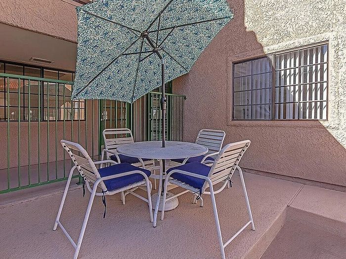 Charming outdoor patio featuring a round table with chairs and a vibrant umbrella, ideal for relaxing in style and comfort.