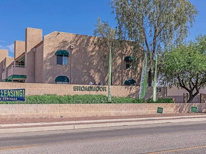 Charming apartment complex exterior with attractive landscaping and prominent leasing announcement.