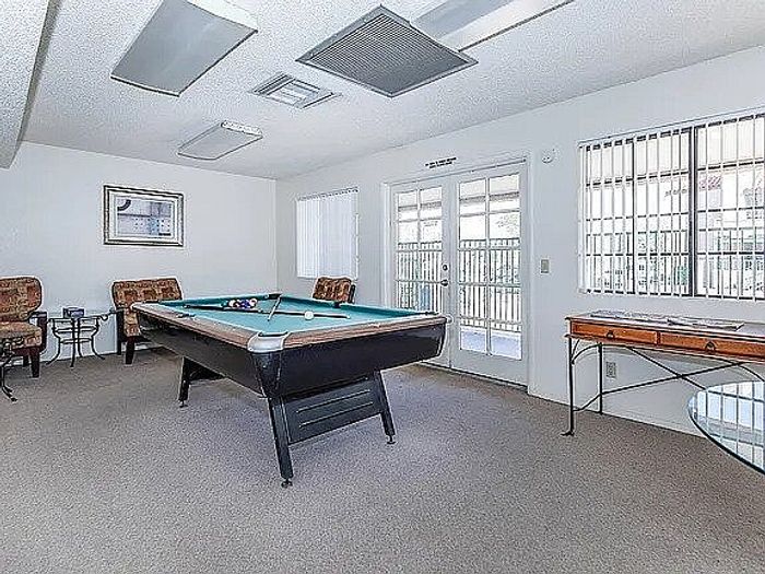 Bright game room with a stylish pool table, comfortable seating, and glass doors leading to a balcony.