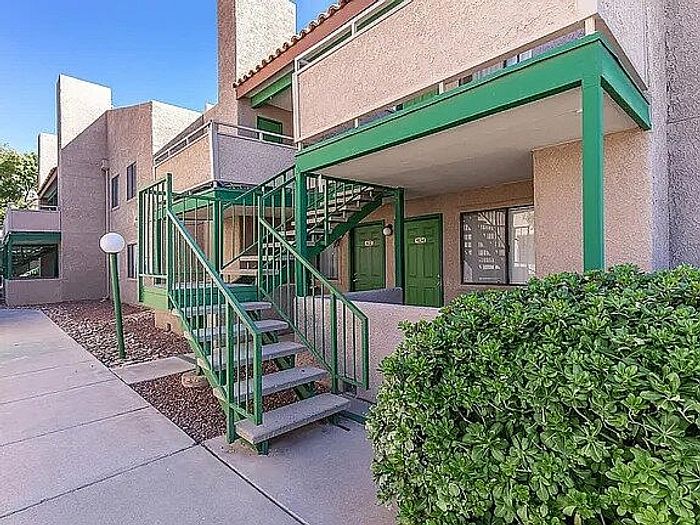 Charming apartment exterior with green accents, featuring a modern staircase and lush landscaping.