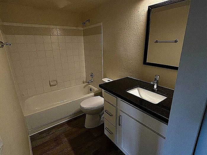 Modern bathroom with elegant dark countertop, sleek sink, and classic bathtub.
