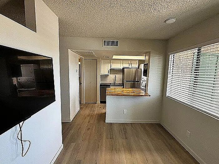 Contemporary apartment interior with open-plan kitchen and living area featuring modern appliances and wooden flooring.
