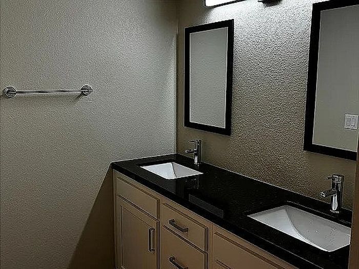 Modern bathroom with elegant black countertop, dual sinks, and stylish frameless mirrors.