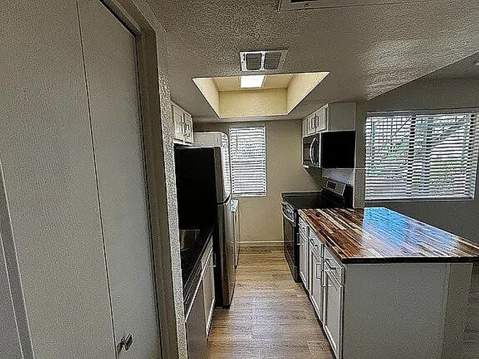 Modern kitchen with stainless steel appliances, beautiful wooden countertops, and ample natural light from skylights and large windows.