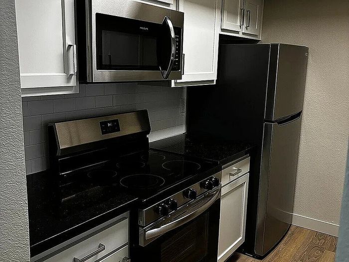 Chic and modern kitchen with sleek stainless steel appliances, elegant white cabinetry, and glossy black countertops.