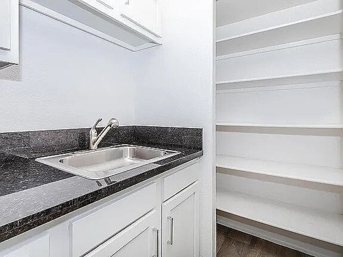 Elegant kitchen space with sleek granite countertops, modern sink, and ample open shelving for storage.
