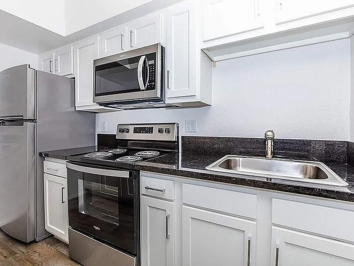 Modern kitchen with sleek stainless steel appliances, elegant dark countertops, and crisp white cabinetry.