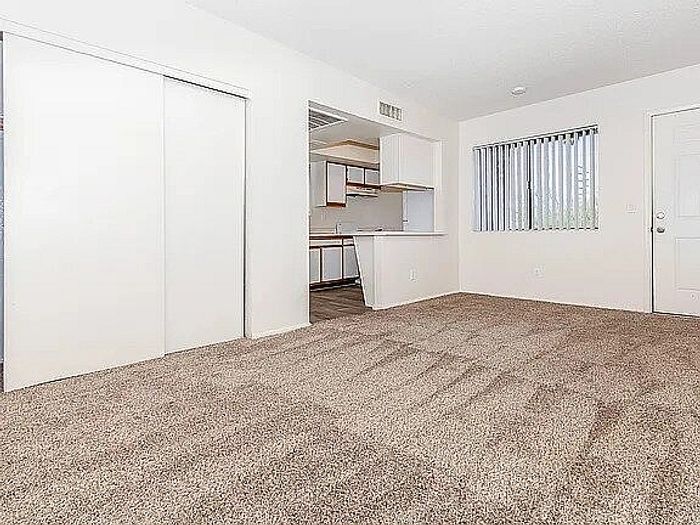 Bright and inviting open-concept living area with plush carpet and access to a modern kitchen.