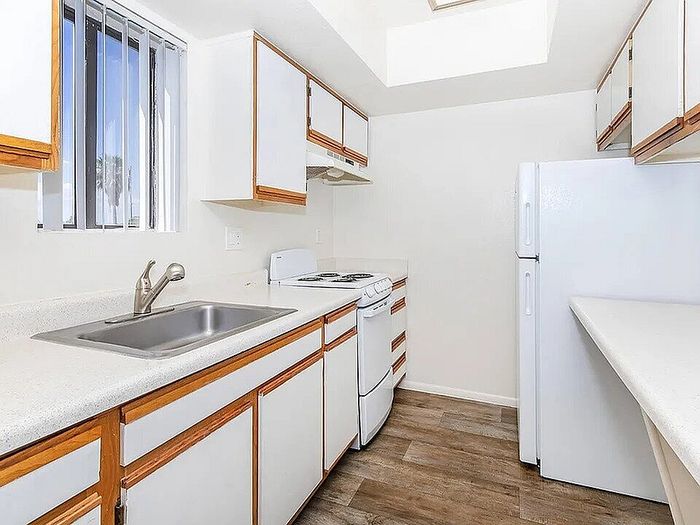 Bright and inviting kitchen featuring modern appliances, ample cabinetry, and a sleek countertop with natural light streaming through a window.