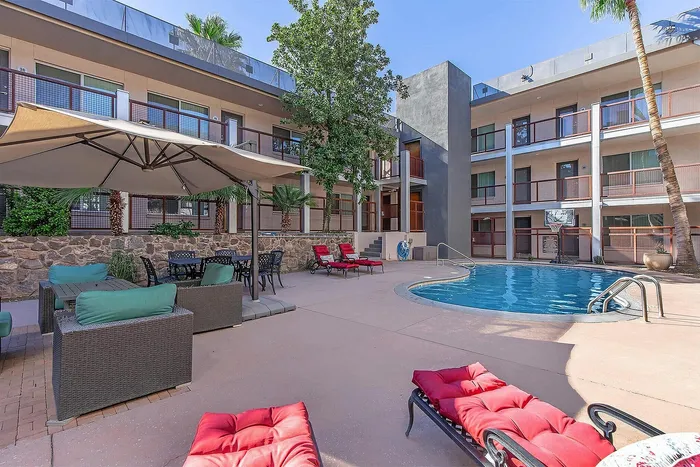 Chic apartment complex with inviting poolside lounge, stylish outdoor seating, and lush greenery for a serene getaway.
