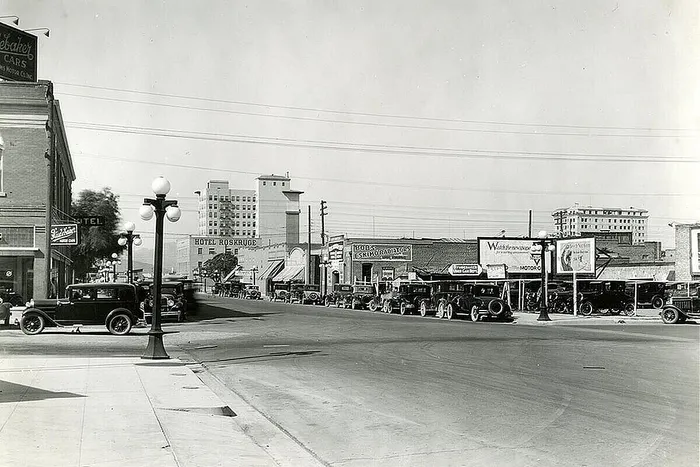 Charming vintage cityscape with classic automobiles lined along a bustling street, showcasing historical architecture and retro signage.