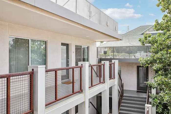 Modern apartment exterior with sleek design, featuring private balconies and lush greenery, perfect for urban living.