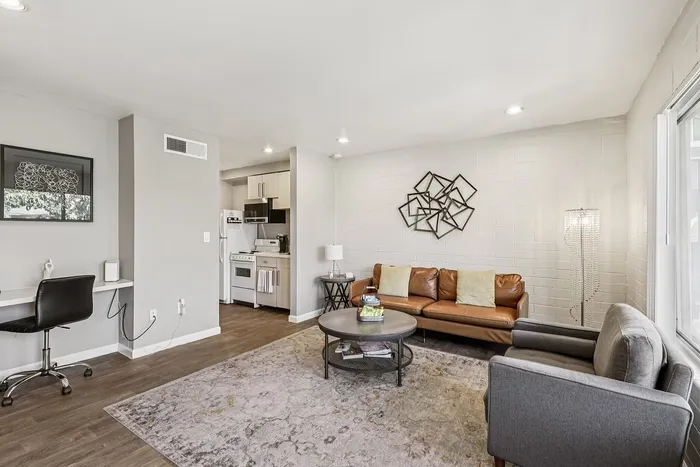 Inviting living area with modern decor, featuring a cozy leather sofa, stylish wall art, and an elegant open kitchen layout.