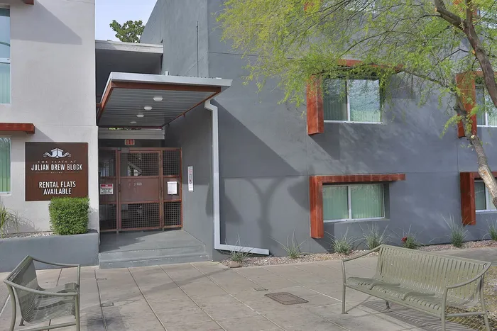 Modern apartment building exterior with rental flats available, featuring clean architectural design and inviting outdoor seating.
