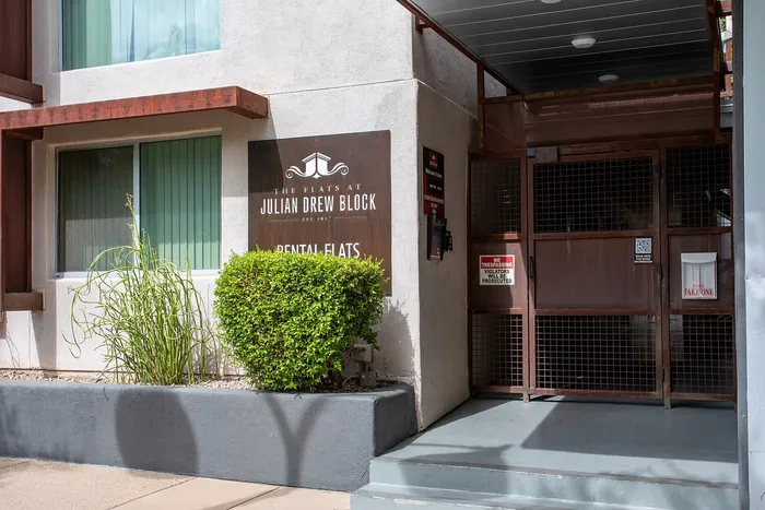 Inviting entrance to Julian Drew Block with modern design, lush greenery, and secure gated entry, showcasing charm and sophistication.