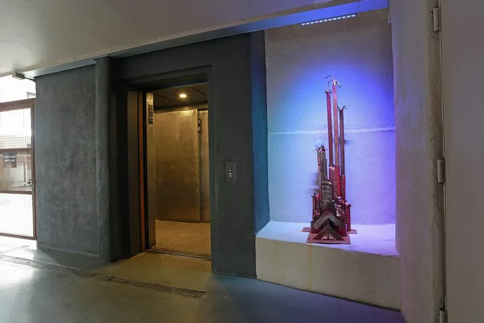 Modern apartment entrance featuring sleek elevator doors and artistic sculpture with vibrant lighting.