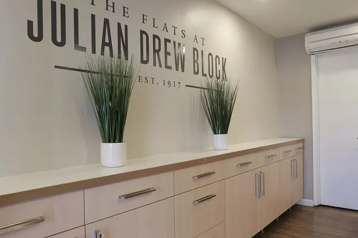 Modern hallway at Julian Drew Block featuring sleek cabinetry and elegant potted greenery, showcasing contemporary style and warm ambiance.