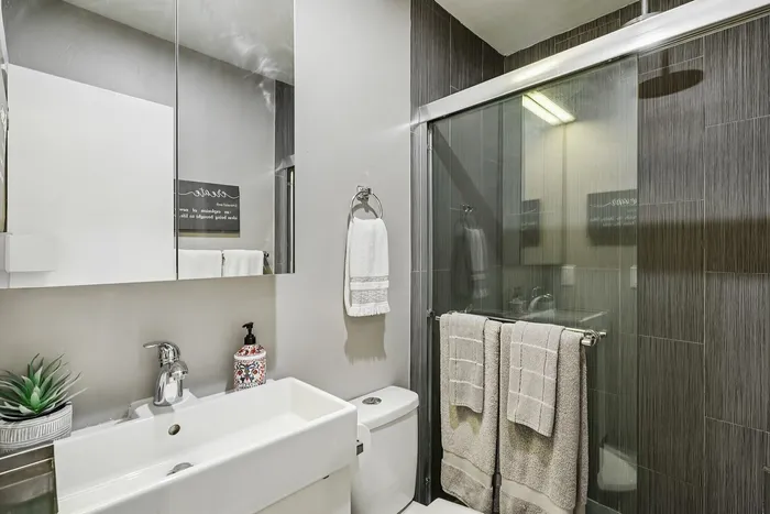 Modern bathroom featuring sleek fixtures, glass shower enclosure, and stylish decor with towel accents.