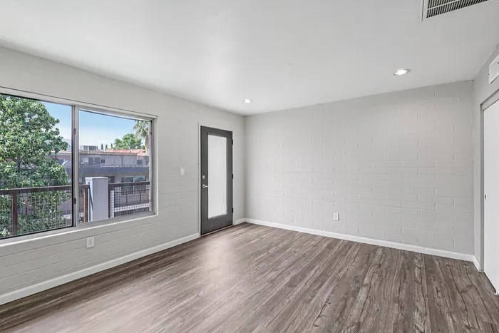 Bright and airy room with large windows showcasing a stunning outdoor view, sleek hardwood floors, and minimalist design.