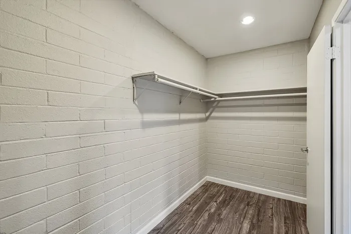 Spacious walk-in closet with modern wood flooring and ample hanging space, perfect for organization and style.