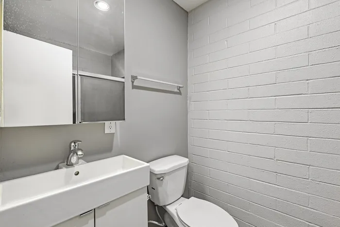 Modern bathroom showcasing a sleek white sink, stylish wall tiles, and contemporary fixtures.