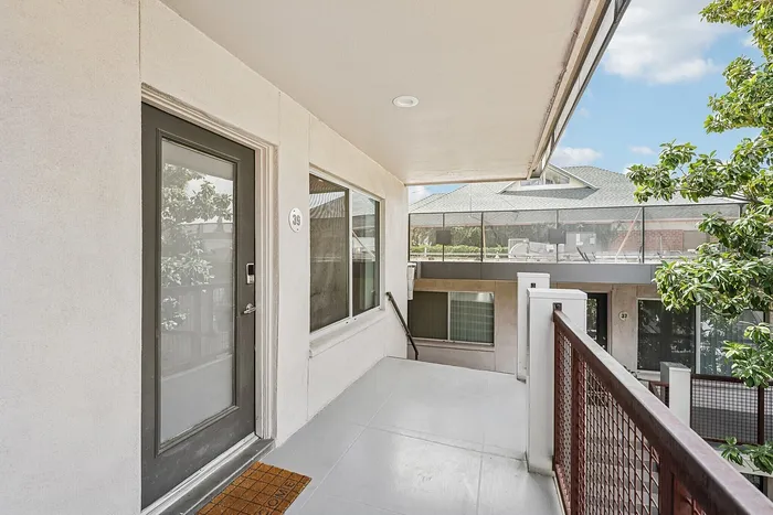 Charming apartment entry with sleek modern door and spacious balcony, offering serene views and abundant natural light.