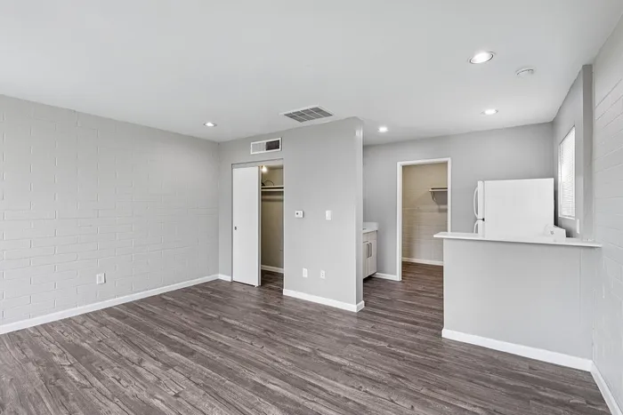Modern open-concept apartment featuring sleek hardwood floors, bright walls, and a spacious kitchen with a breakfast bar.