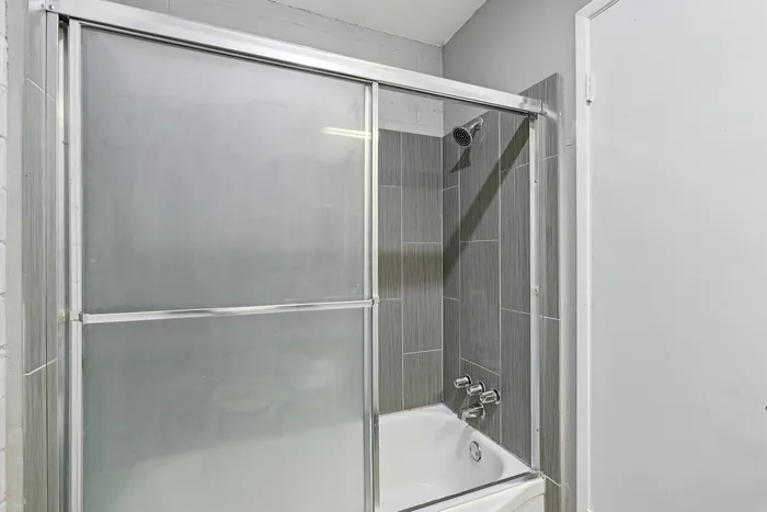 Modern bathroom featuring a sleek glass shower enclosure with elegant gray tile design.