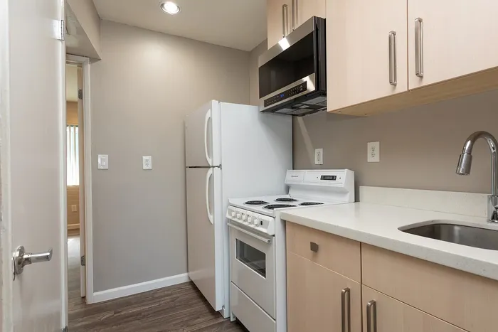Charming kitchen with modern white appliances, sleek cabinetry, and elegant wood flooring, perfect for culinary creativity.