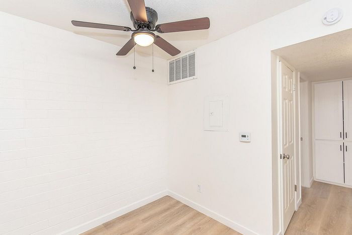 Bright room with modern ceiling fan, white brick wall, and warm wooden flooring, perfect for a cozy space.