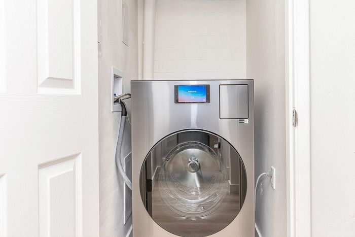 Modern laundry area with a sleek stainless steel front-loading washer in a bright, compact space.
