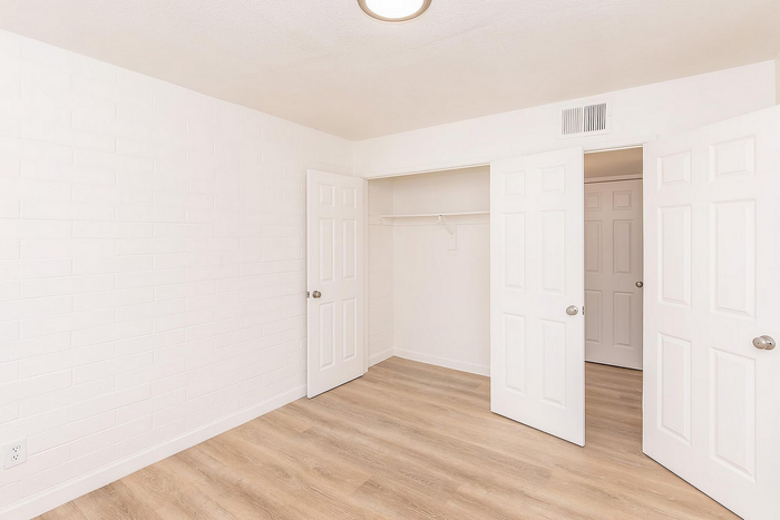 Bright and airy bedroom with elegant wood flooring and spacious closet, perfect for stylish living.