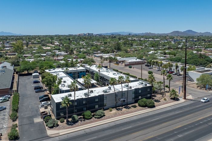 Charming aerial view of a modern apartment complex surrounded by lush greenery and scenic mountain views.