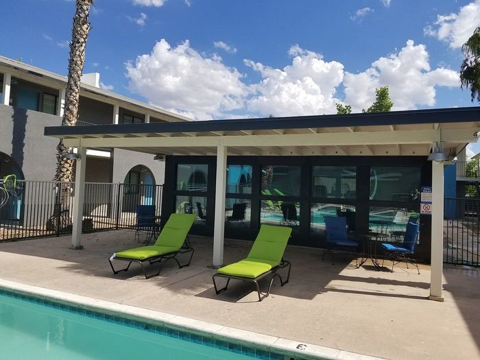 Inviting outdoor pool area with vibrant green lounge chairs under a stylish pergola, perfect for relaxing on a sunny day.