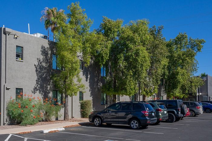 Inviting apartment complex with lush greenery and ample parking under a clear blue sky.