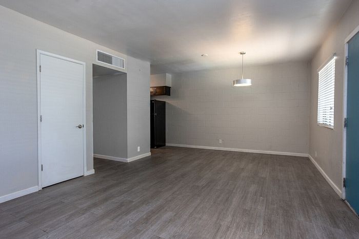 Modern apartment interior featuring sleek gray flooring, a stylish pendant light, and a spacious open living area with abundant natural light. Ideal for contemporary living.